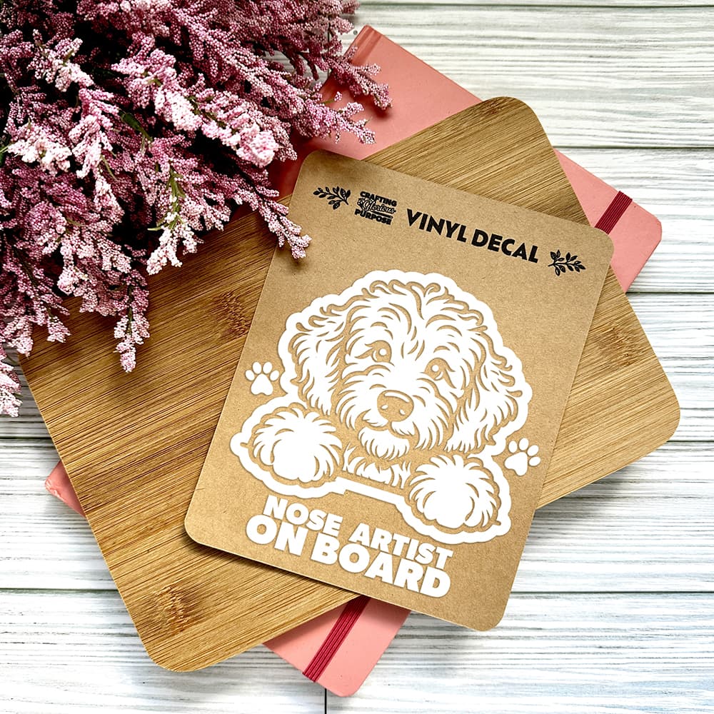 Vinyl decal with a dog illustration and text on a wooden surface with pink flowers.