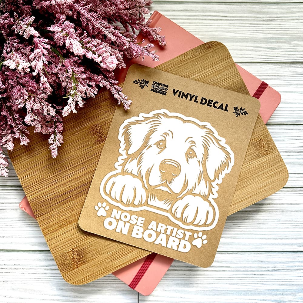 Vinyl decal with a dog illustration and text on a wooden surface with pink flowers.