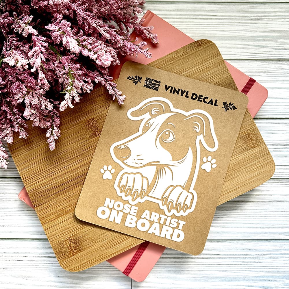 Vinyl decal with a dog illustration and text on a wooden surface with pink flowers.