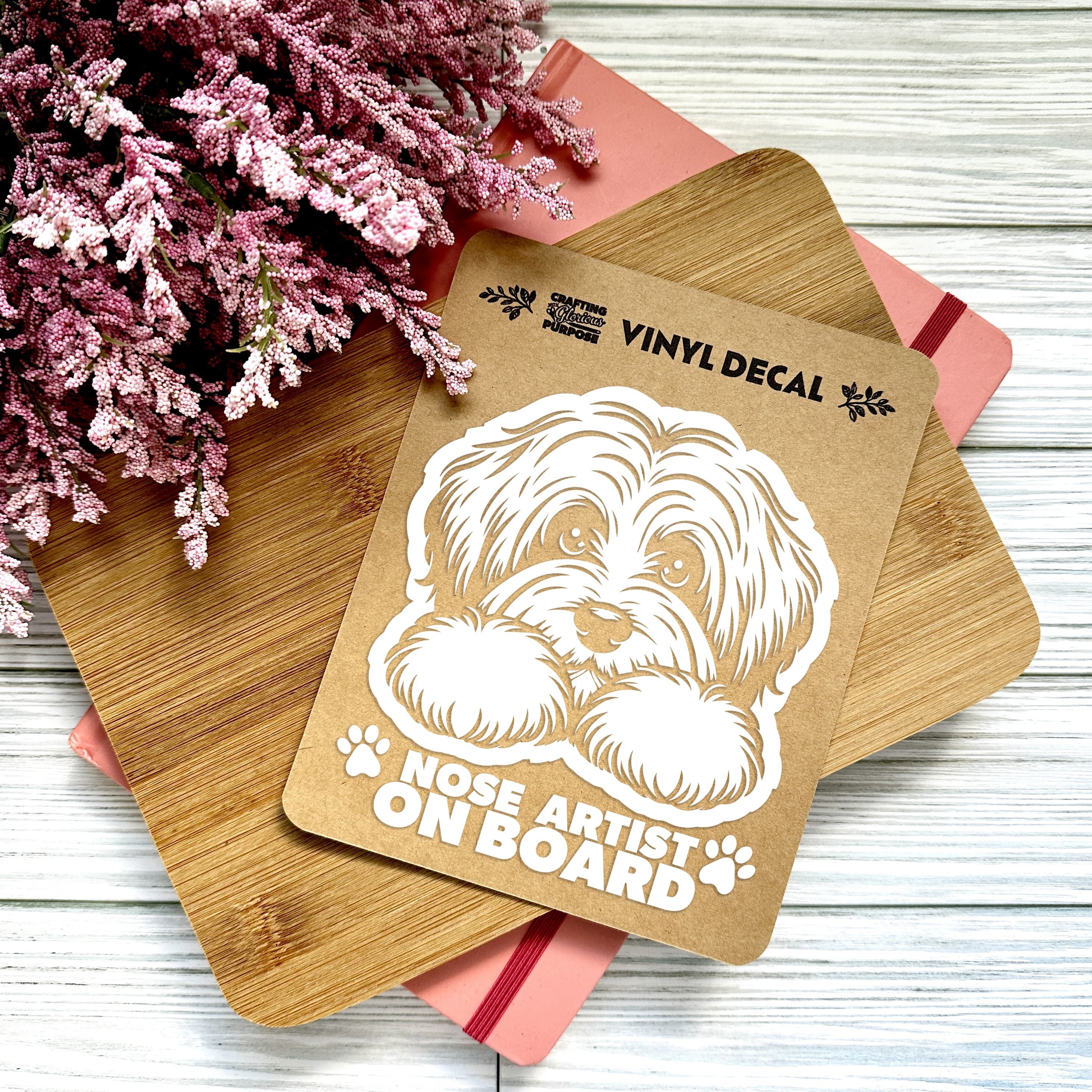 Vinyl decal with a dog illustration and text on a wooden surface with pink flowers.