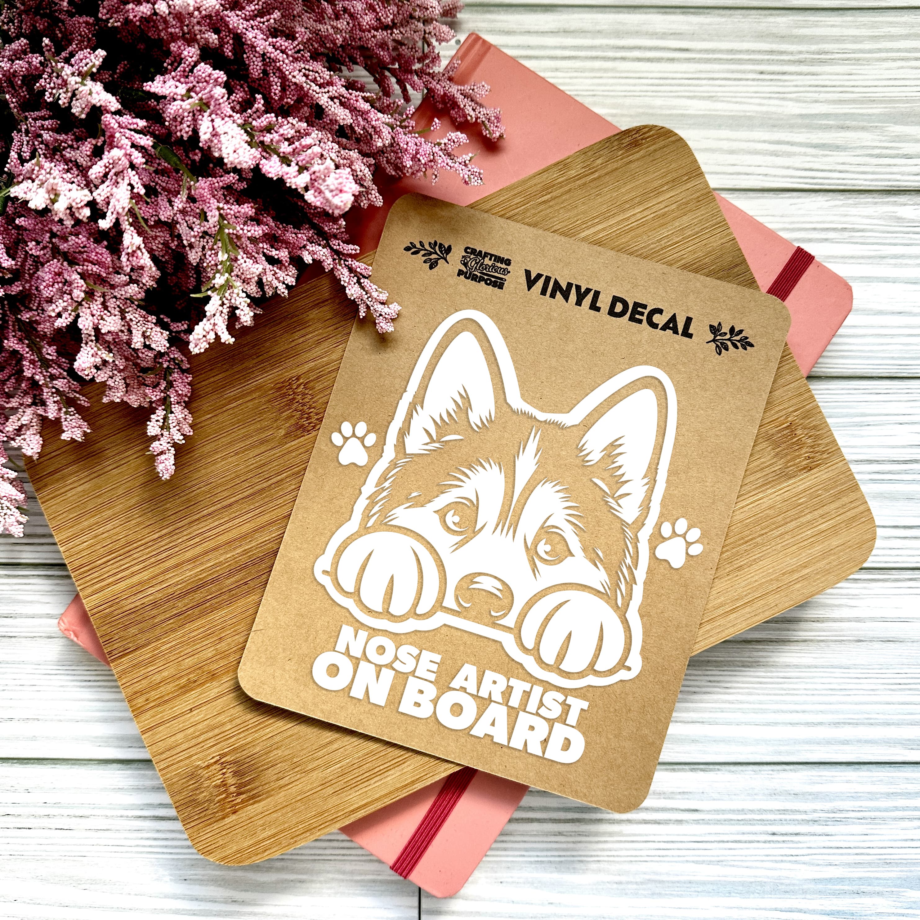 Vinyl decal with a dog illustration and text on a wooden surface with pink flowers.