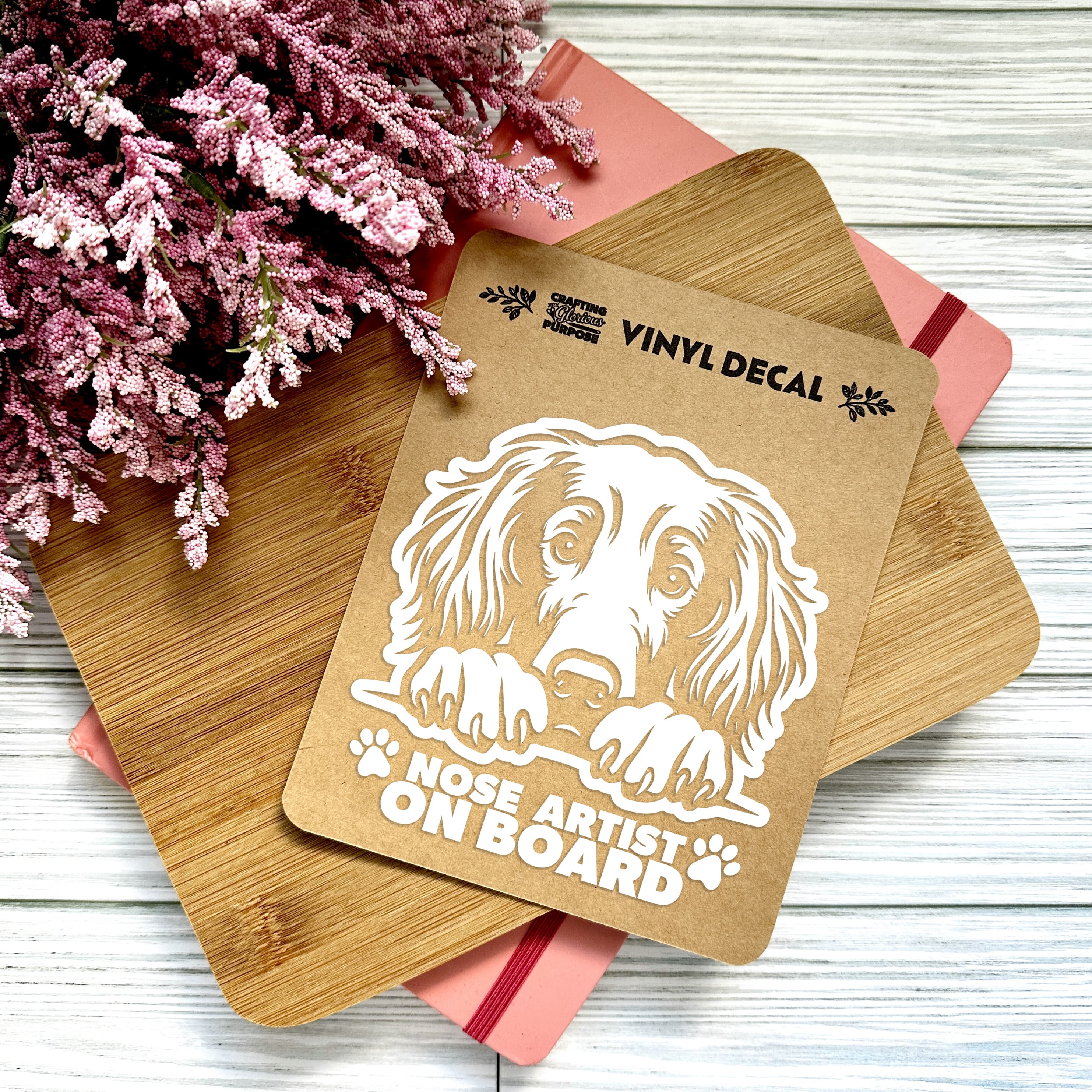 Vinyl decal with a dog illustration and text on a wooden surface with pink flowers.