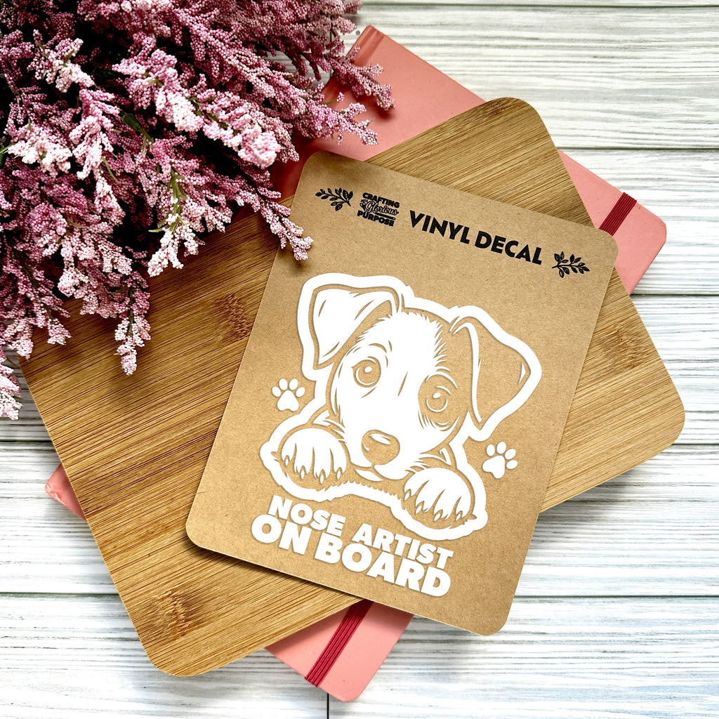 Vinyl decal with a dog illustration and text on a wooden surface with pink flowers.