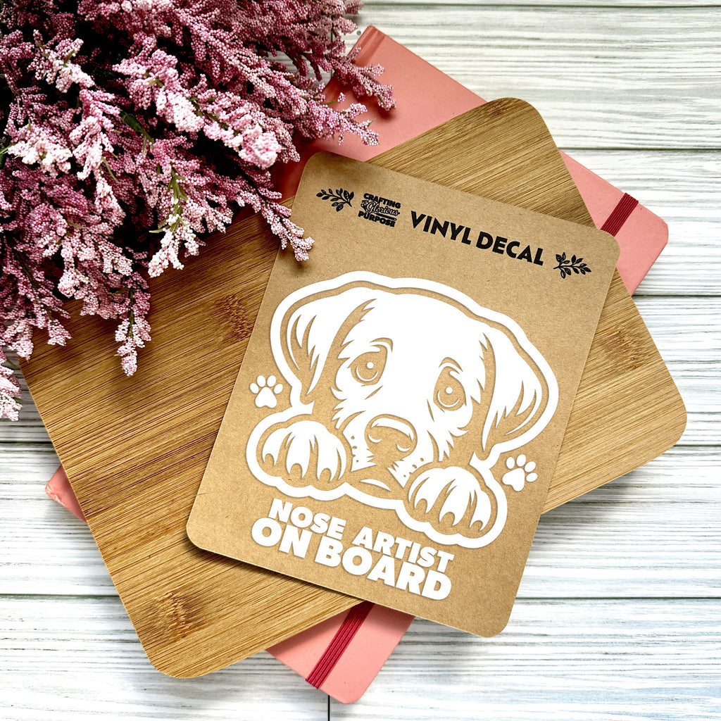 Vinyl decal with a dog illustration and text on a wooden surface with pink flowers.