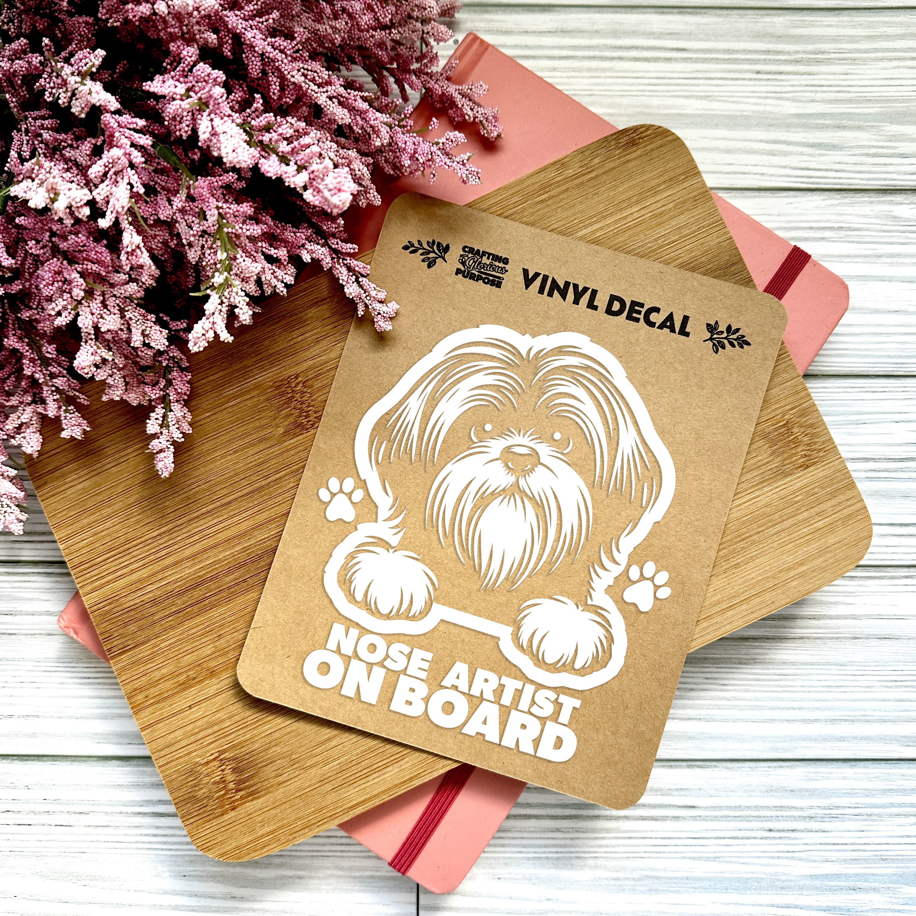 Vinyl decal with a dog illustration and text on a wooden surface with pink flowers.