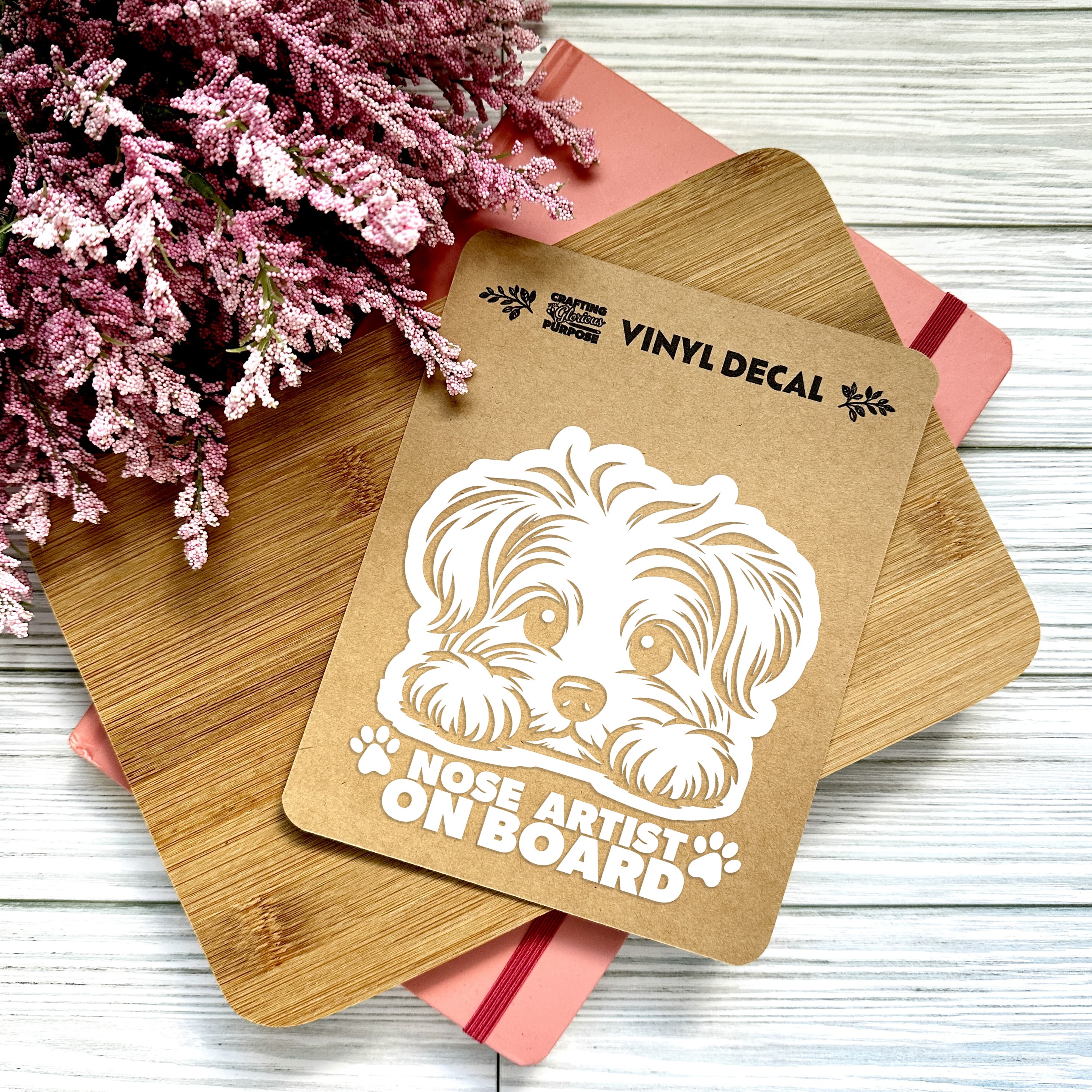 Vinyl decal with a dog illustration and text on a wooden surface with pink flowers.