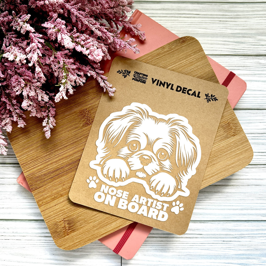 Vinyl decal with a dog illustration and text on a wooden surface with pink flowers.