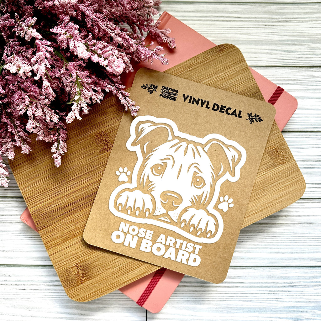 Vinyl decal with a dog illustration and text on a wooden surface with pink flowers.