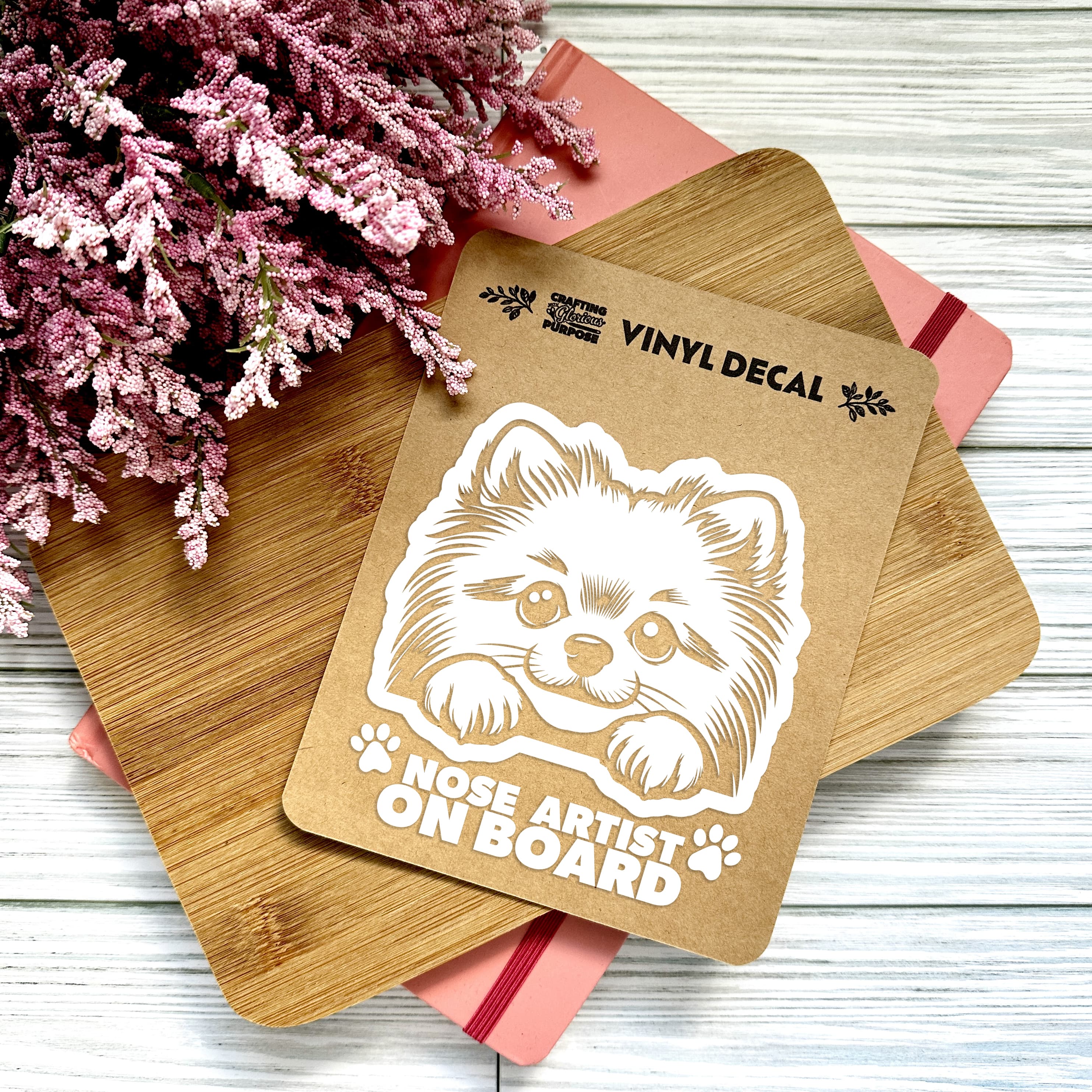 Vinyl decal with a dog illustration and text on a wooden surface with pink flowers.