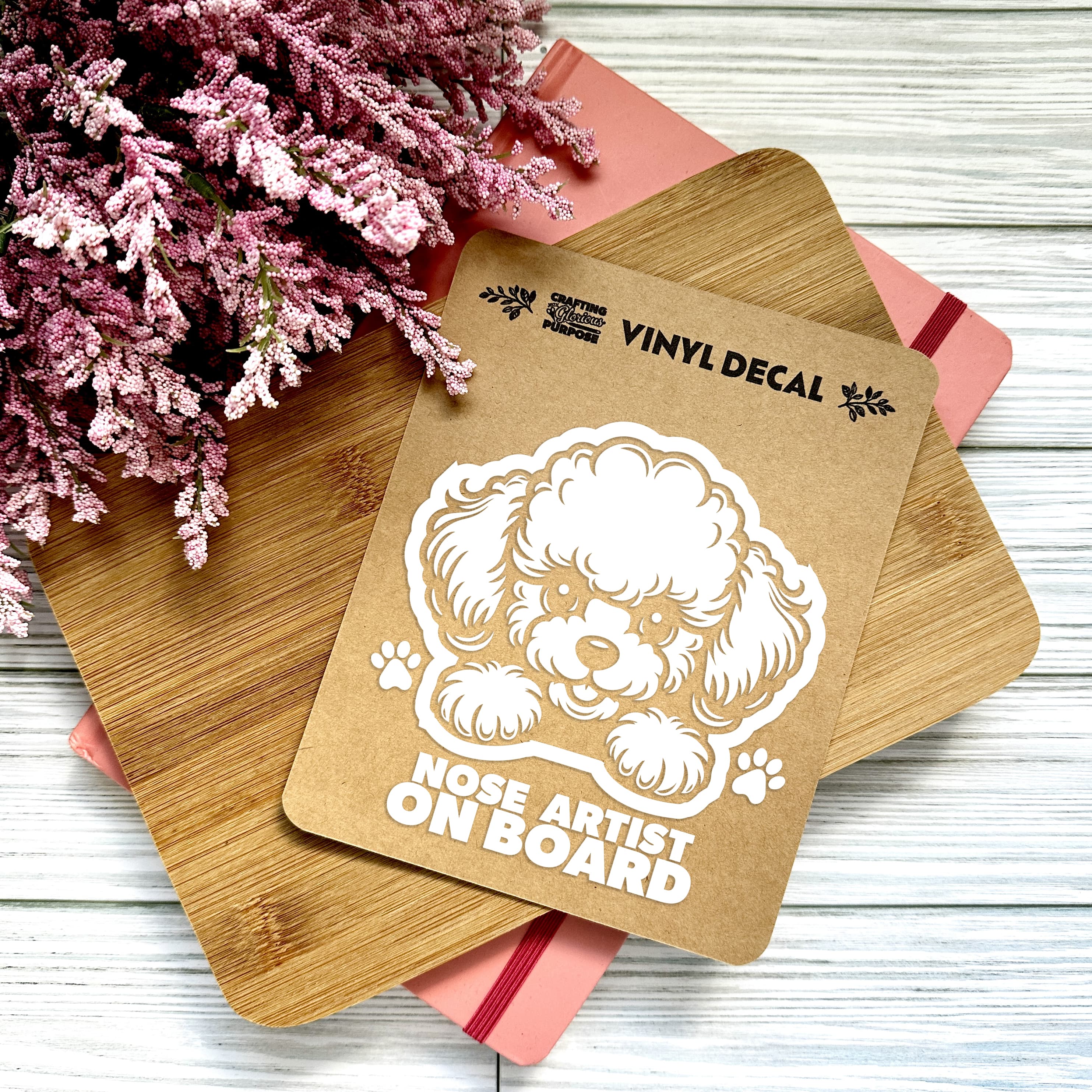 Vinyl decal with a dog illustration and text on a wooden surface with pink flowers.