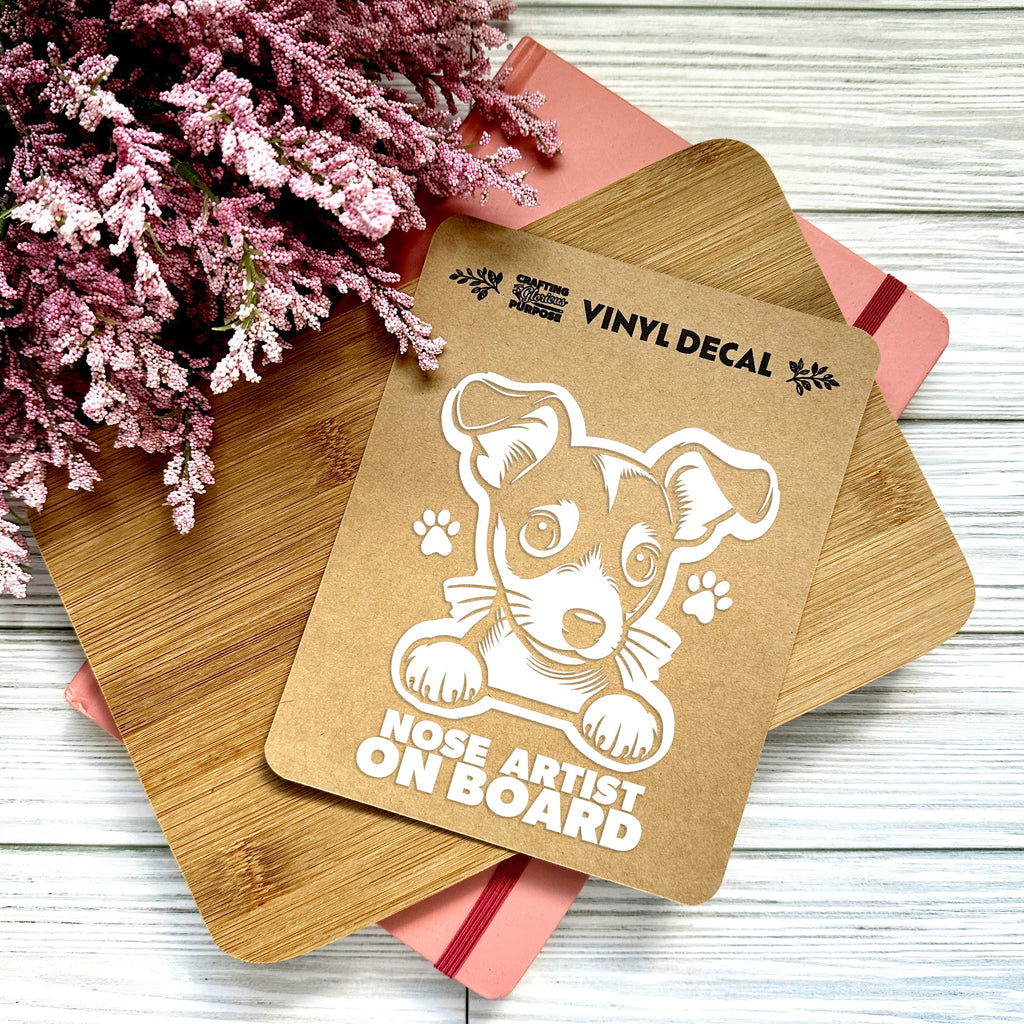 Vinyl decal with a dog illustration and text on a wooden surface with pink flowers.