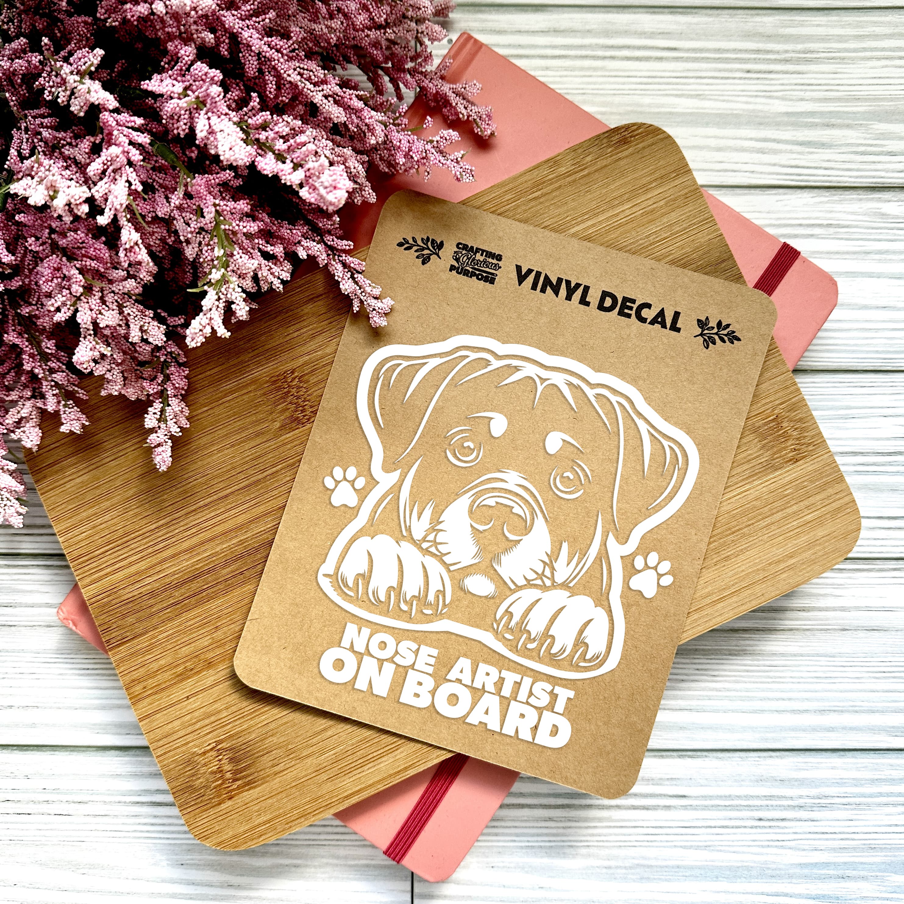 Vinyl decal with a dog illustration and text on a wooden surface with pink flowers.