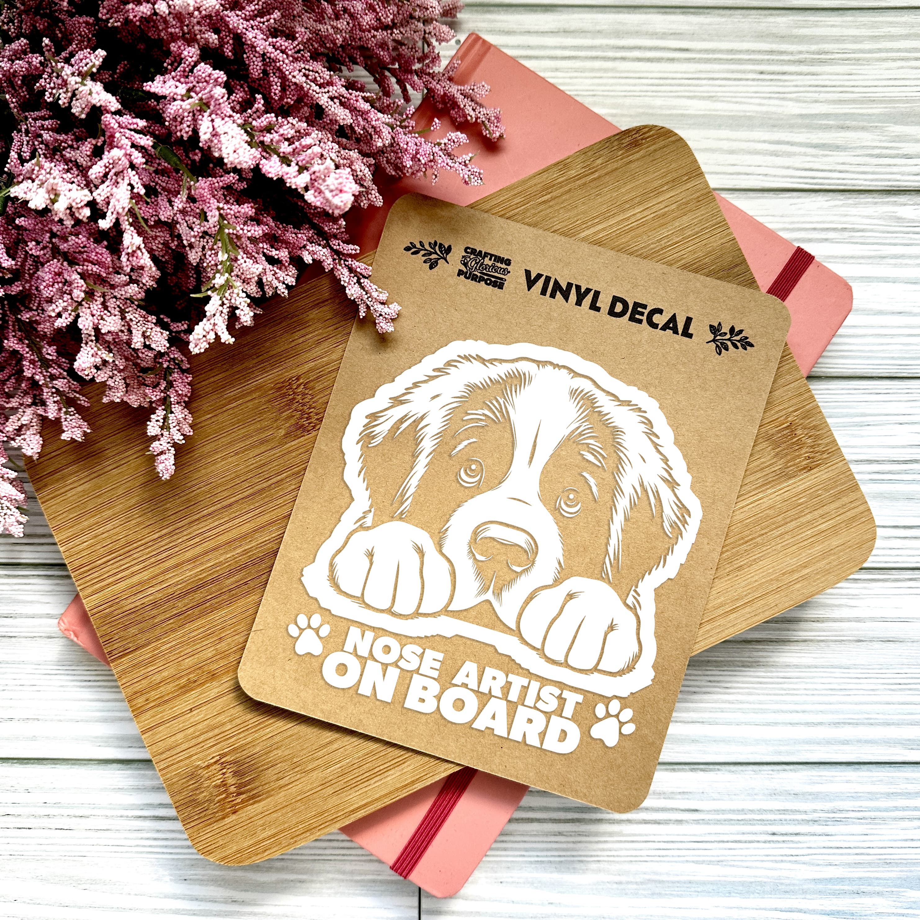 Vinyl decal with a dog illustration and text on a wooden surface with pink flowers.