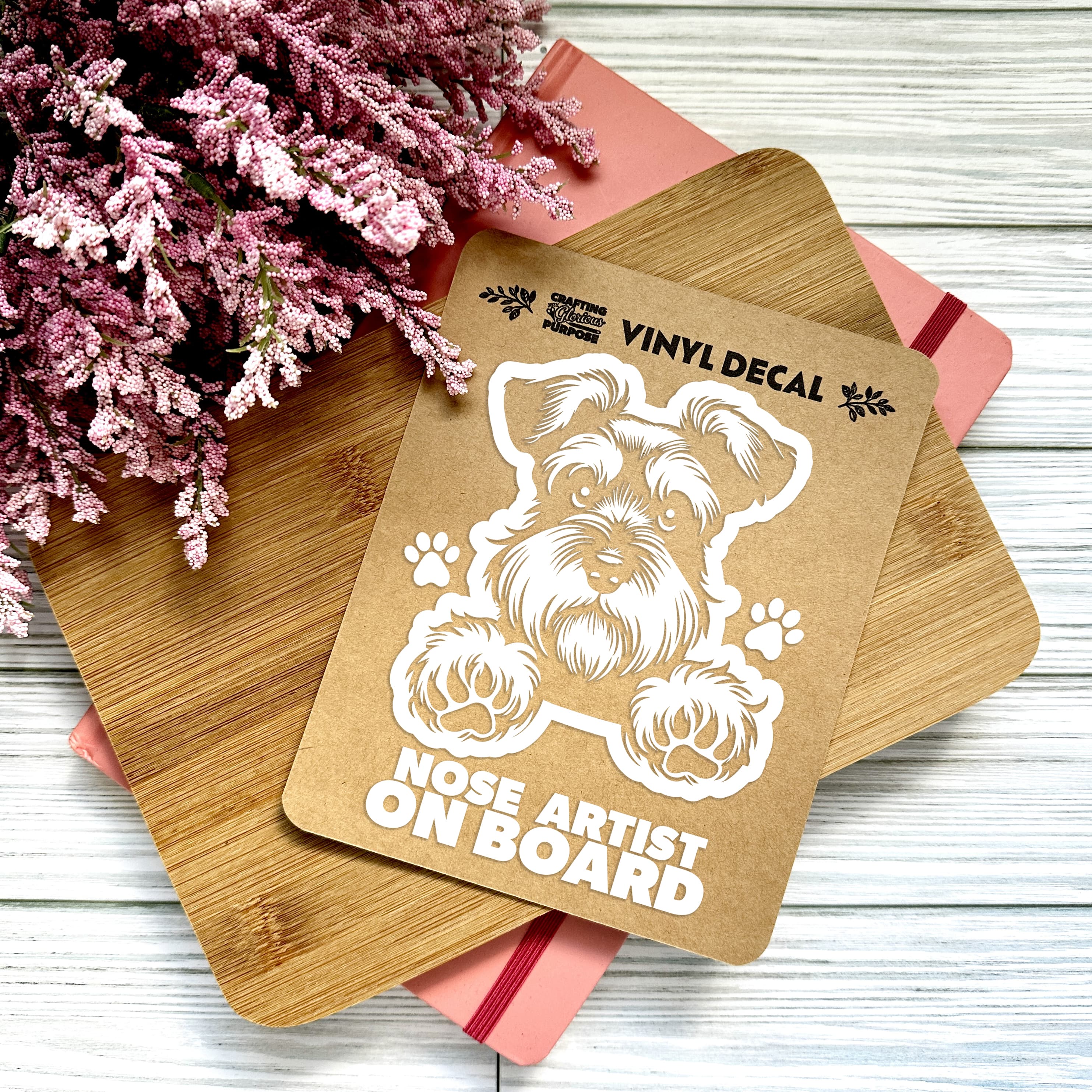 Vinyl decal with a dog illustration and text on a wooden surface with pink flowers.