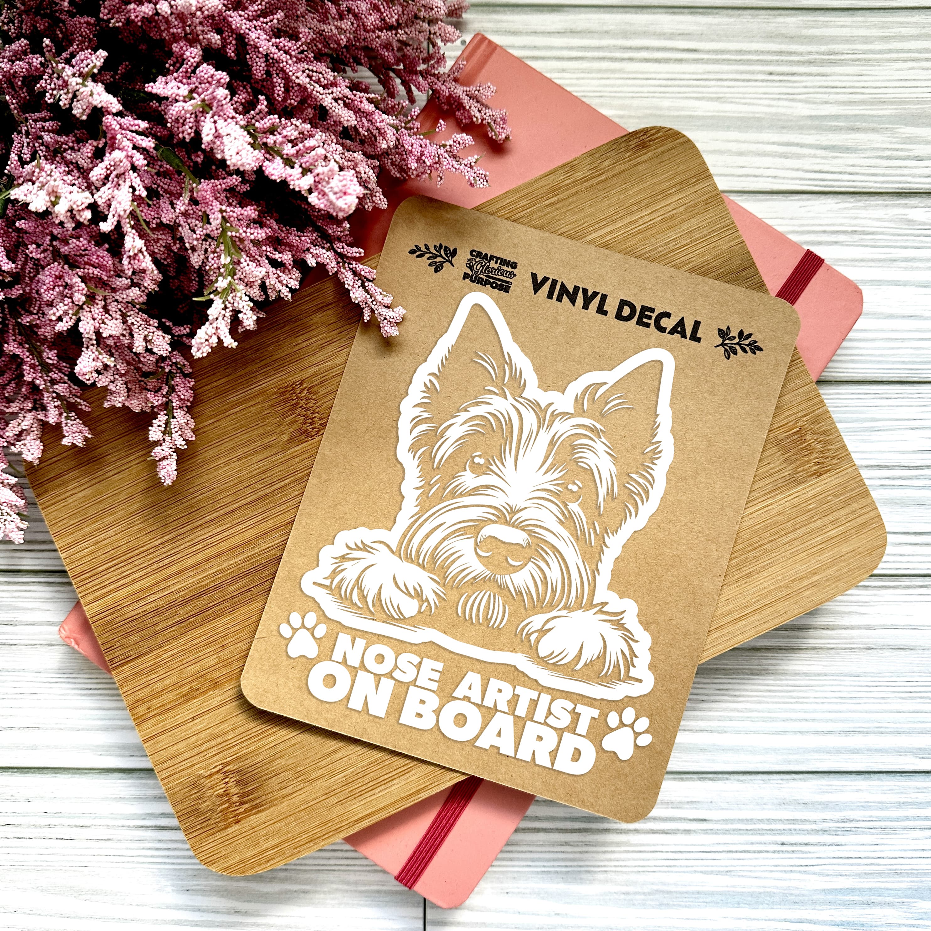 Vinyl decal with a dog illustration and text on a wooden surface with pink flowers.