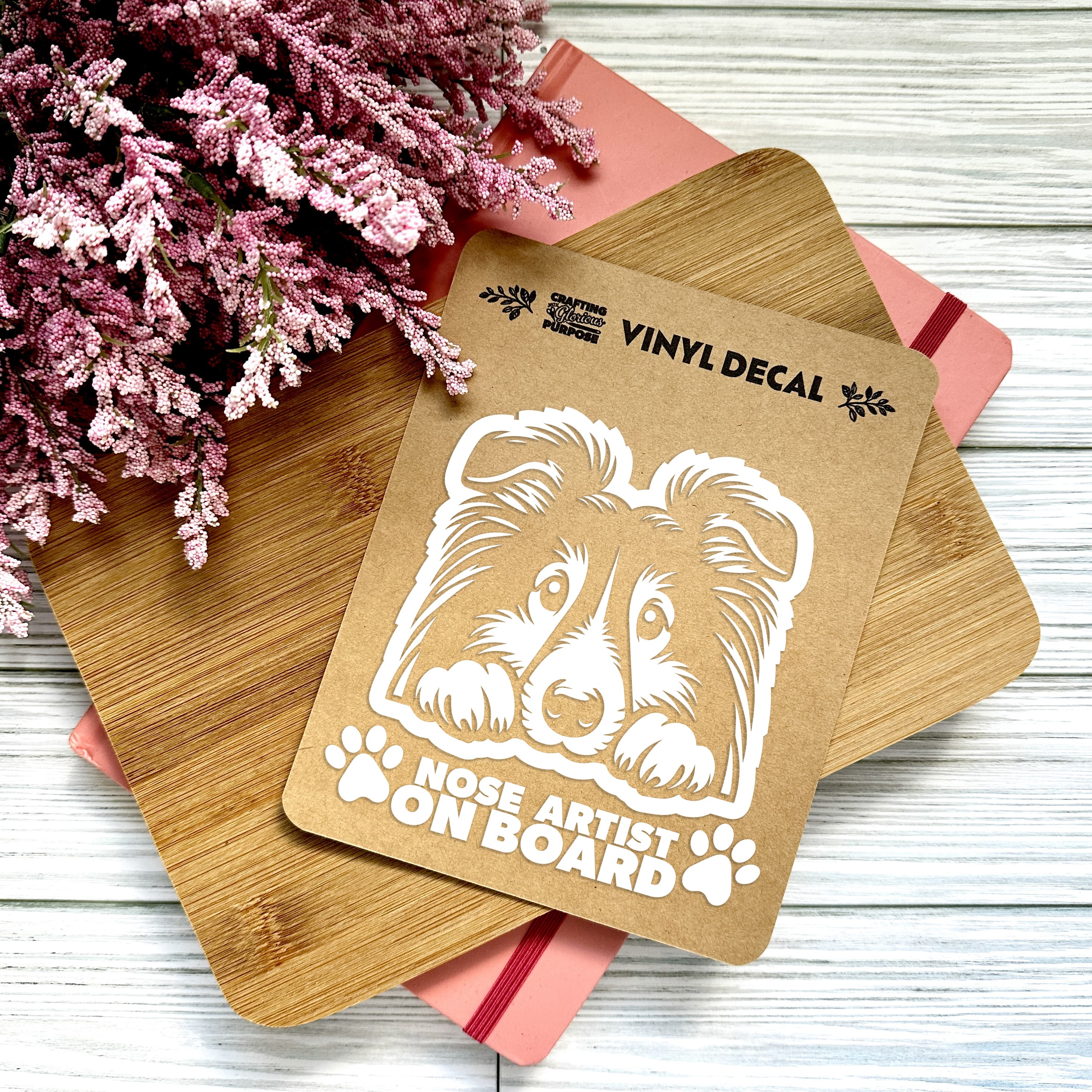 Vinyl decal with a dog illustration and text on a wooden surface with pink flowers.