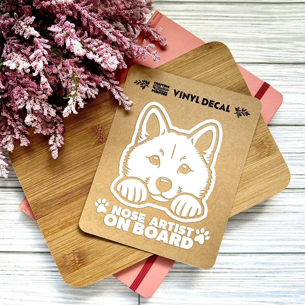 Vinyl decal with a dog illustration and text on a wooden surface with pink flowers.