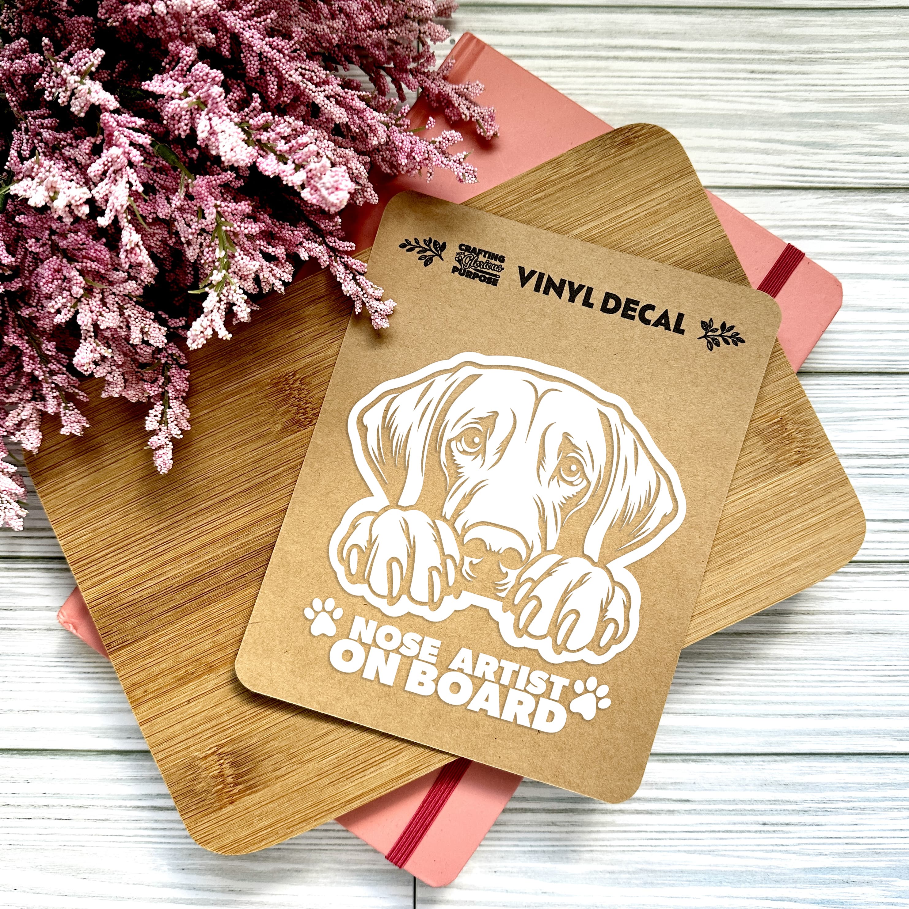 Vinyl decal with a dog illustration and text on a wooden surface with pink flowers.