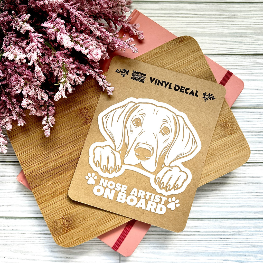 Vinyl decal with a dog illustration and text on a wooden surface with pink flowers.