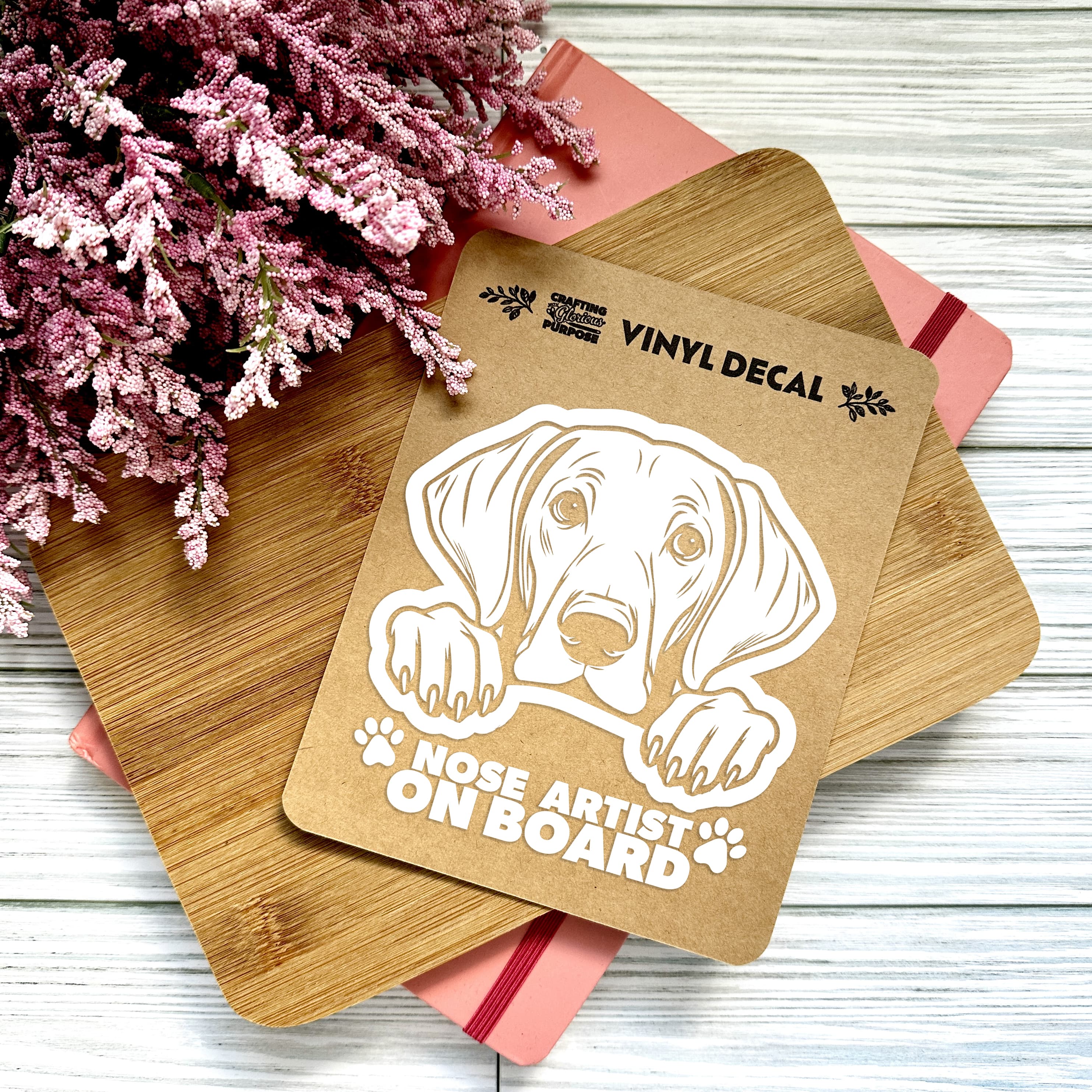 Vinyl decal with a dog illustration and text on a wooden surface with pink flowers.