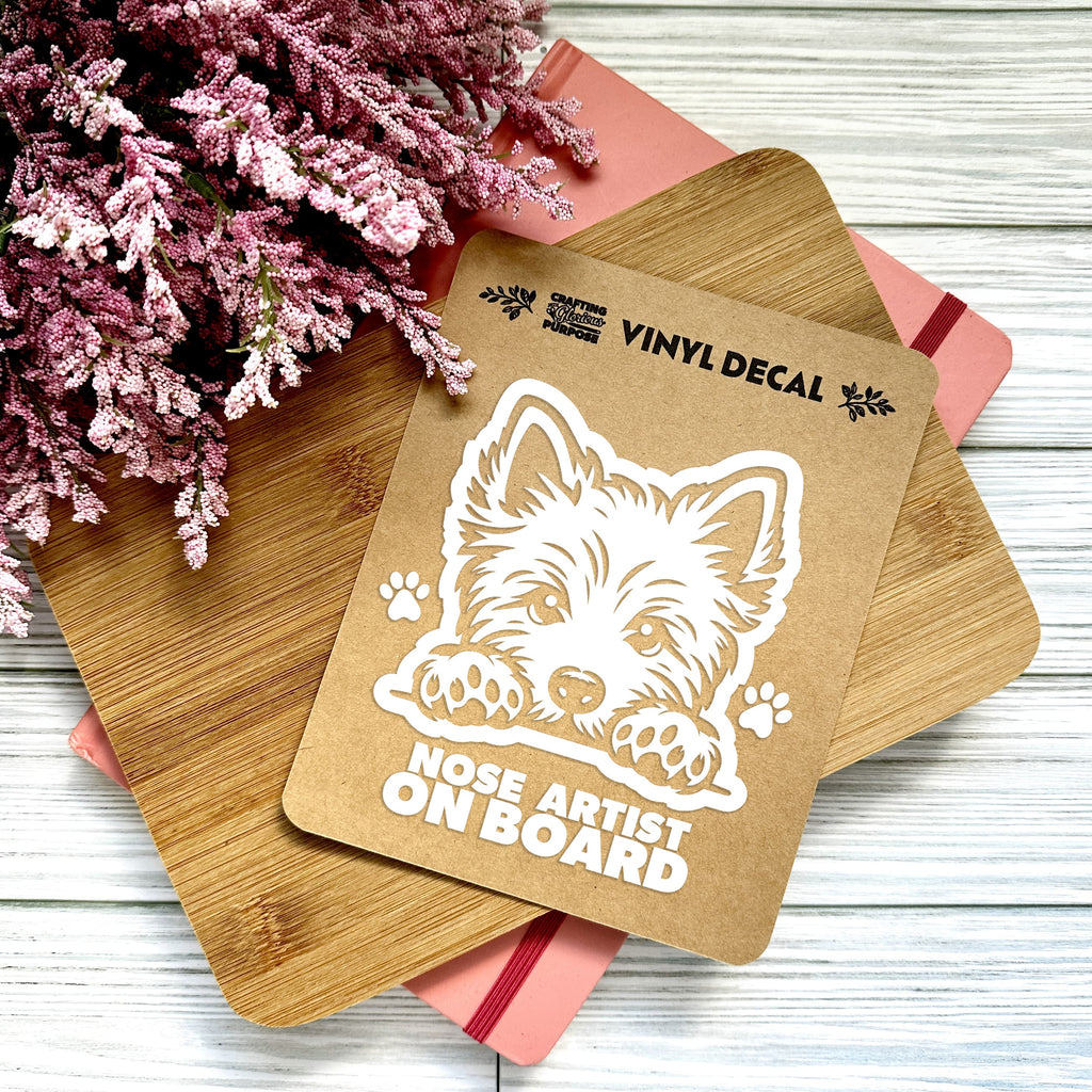 Vinyl decal with a dog illustration and text on a wooden surface with pink flowers.