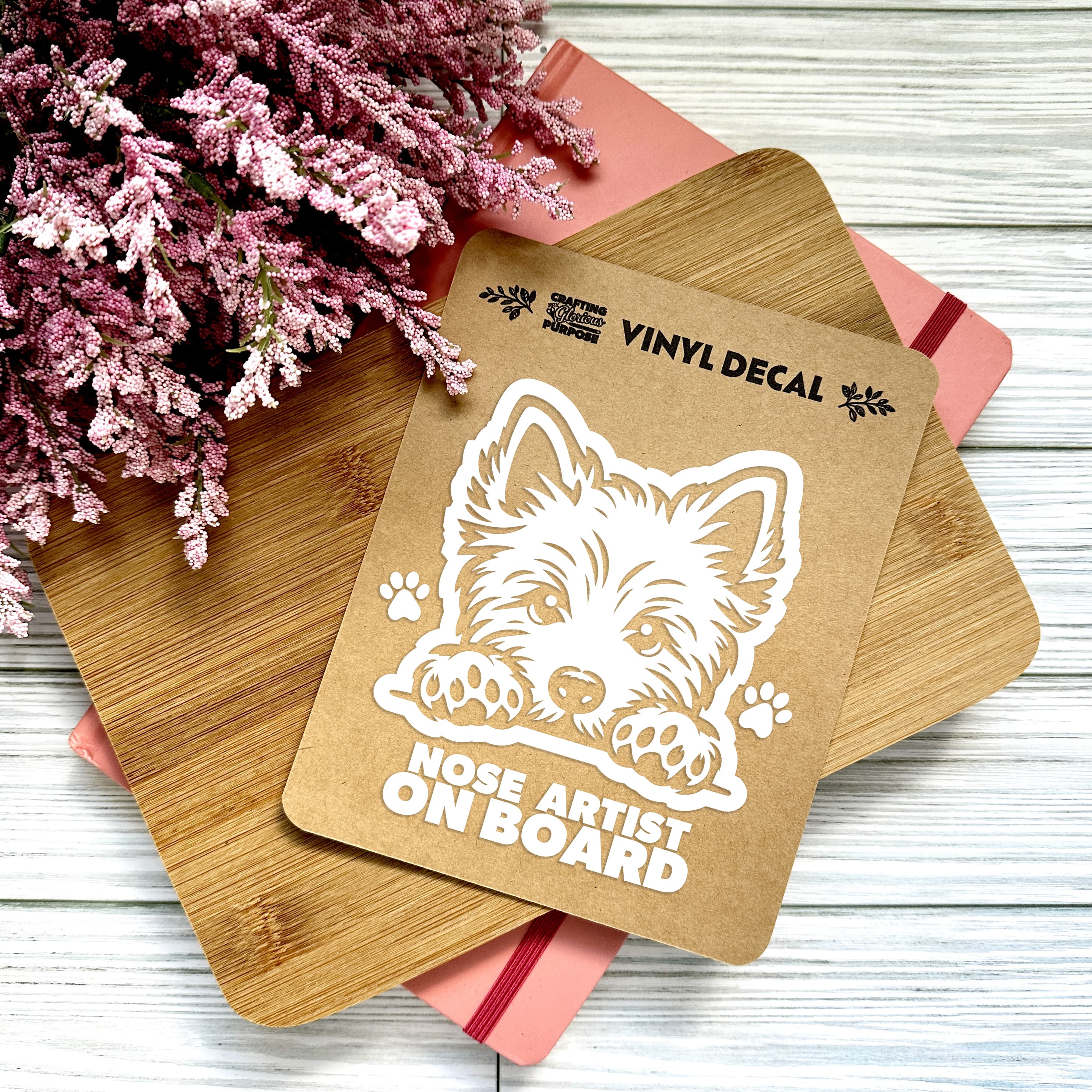 Vinyl decal with a dog illustration and text on a wooden surface with pink flowers.