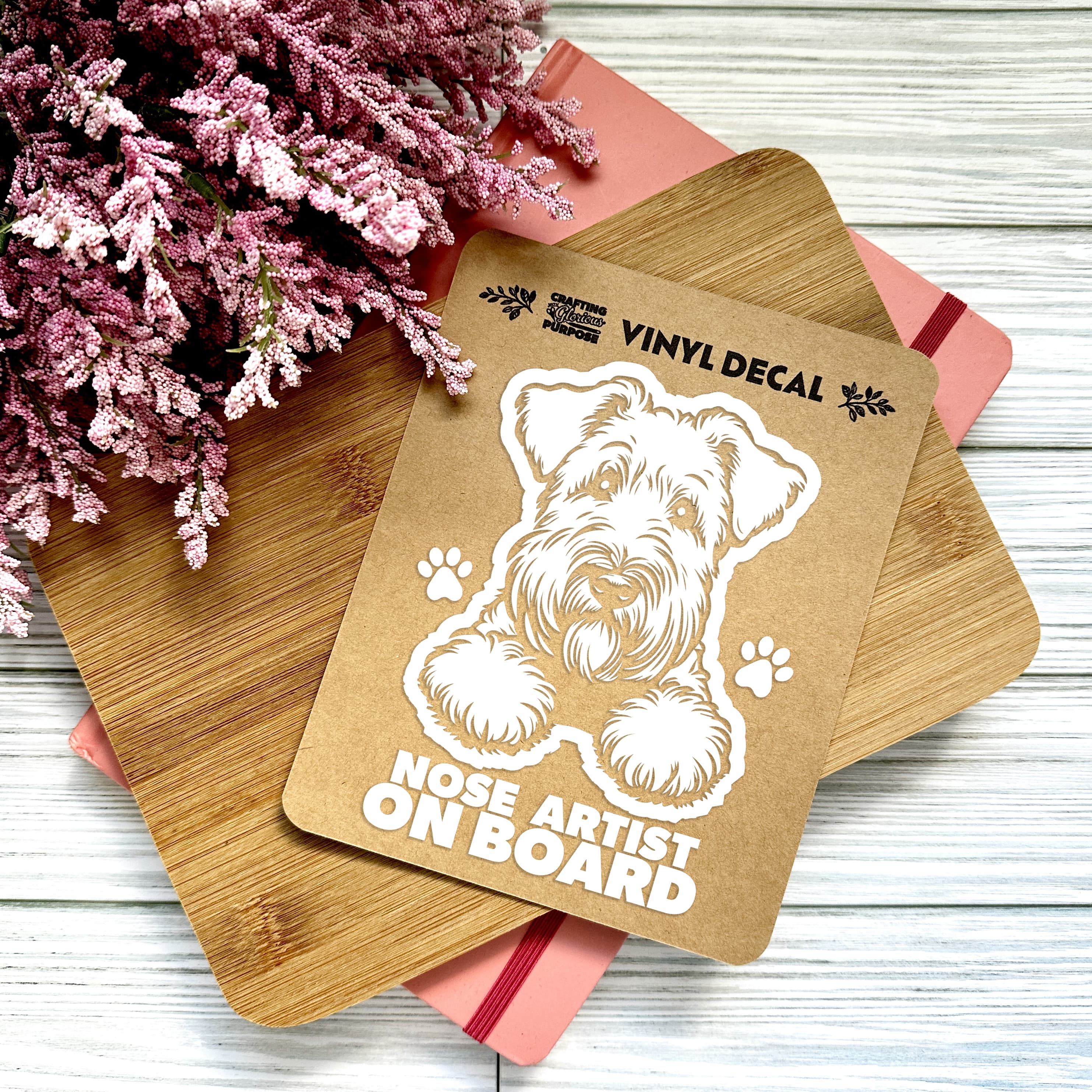 Vinyl decal with a dog illustration and text on a wooden surface with pink flowers.