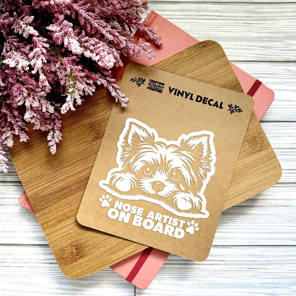 Vinyl decal with a dog illustration and text on a wooden surface with pink flowers.