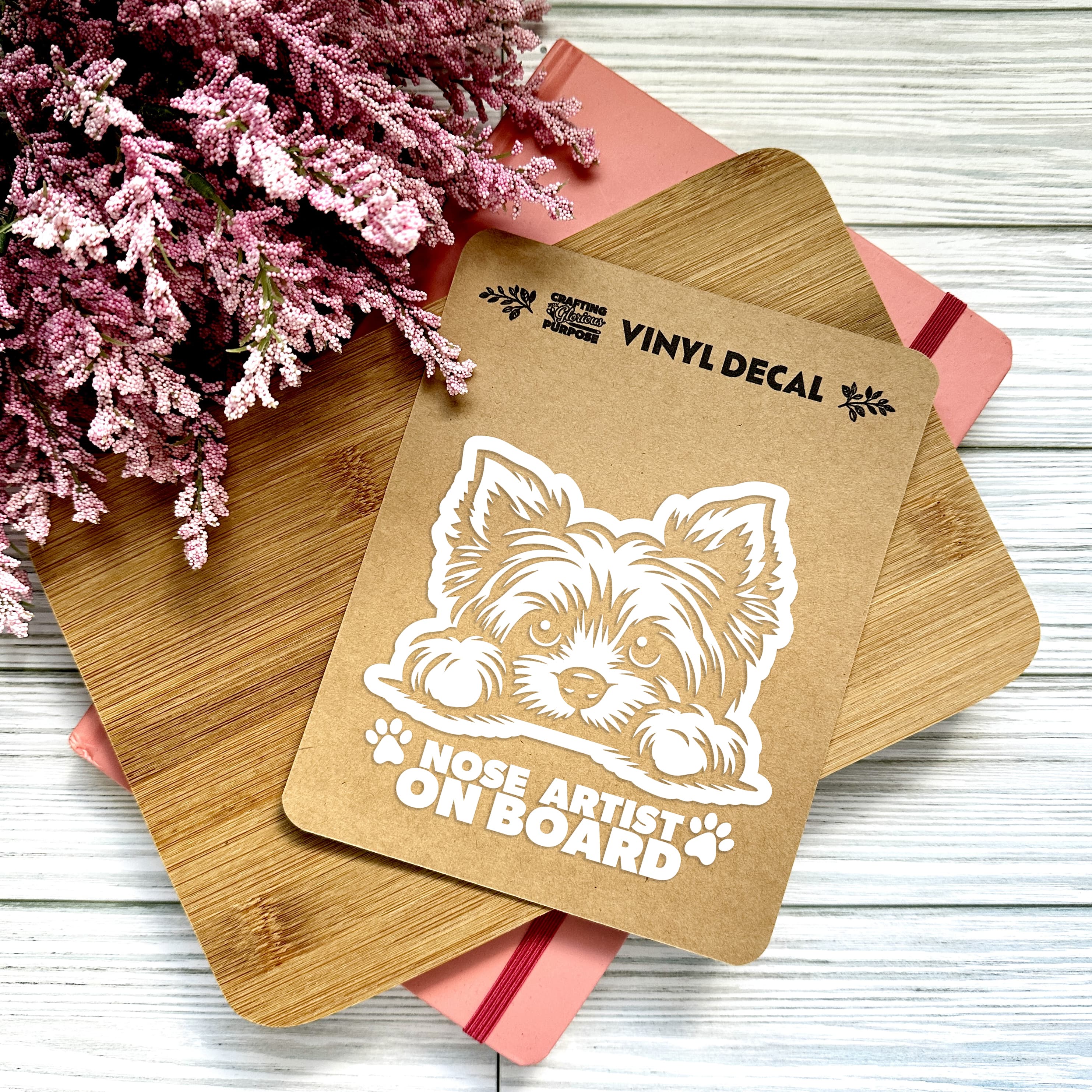 Vinyl decal with a dog illustration and text on a wooden surface with pink flowers.