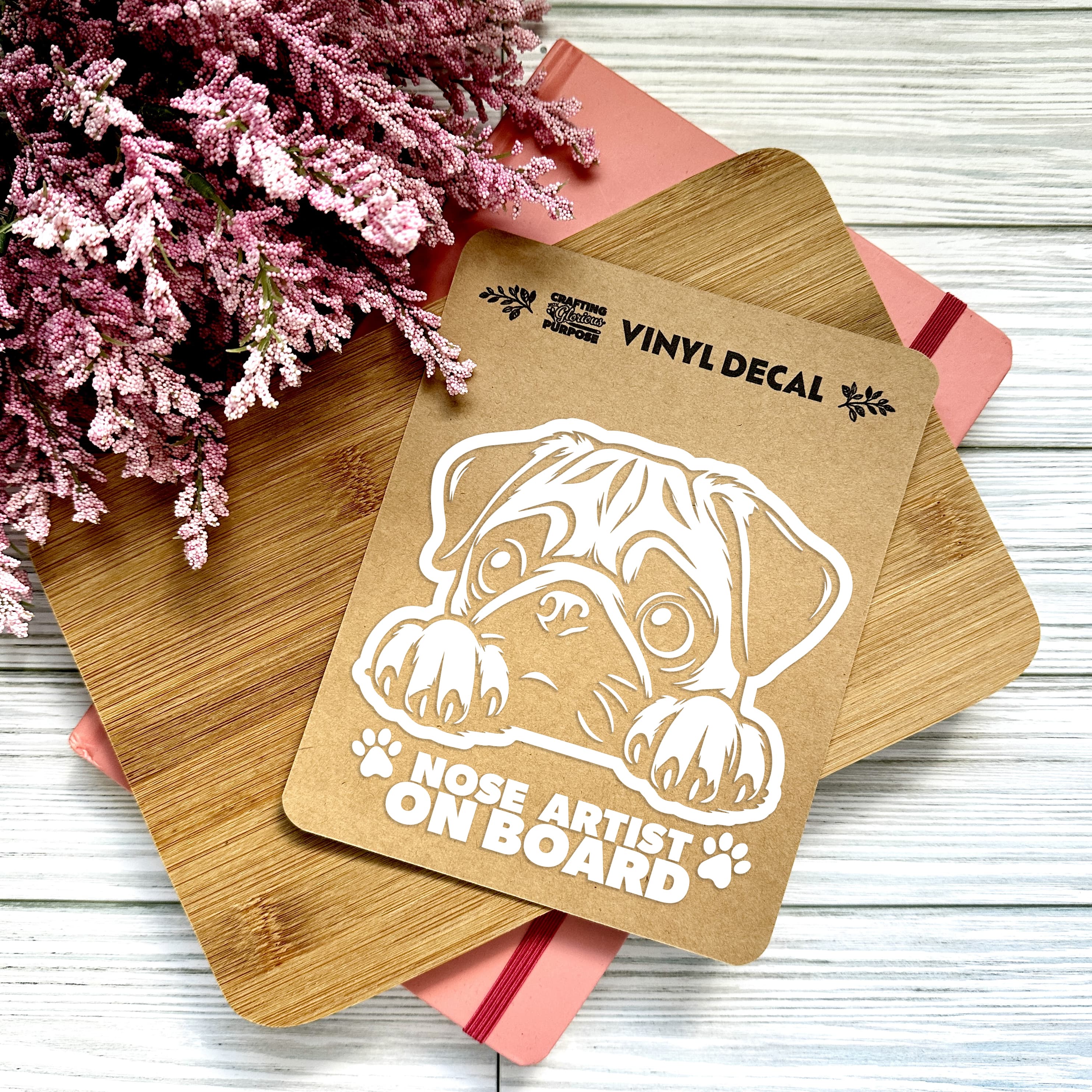 Vinyl decal with a dog illustration and text on a wooden surface with pink flowers.