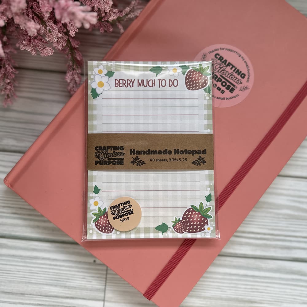 Handmade notepad with strawberry design on a pink surface