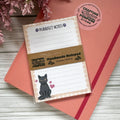 Notepad with 'Purrfect Notes' text and a cat illustration on a pink surface with flowers.