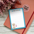Notepad with 'Things to Fetch' text and a dog illustration on a wooden surface with flowers.