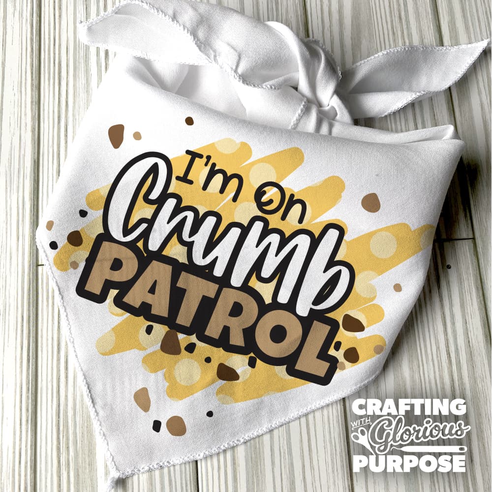 White bandana with 'I'm on Crumb Patrol' text and yellow polka dots on a wooden surface, with 'Crafting with Glorious Purpose' branding.