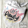 White bandana with 'Let's Pawty!' text and colorful design on a wooden surface, featuring the brand 'Crafting with Glorious Purpose'.