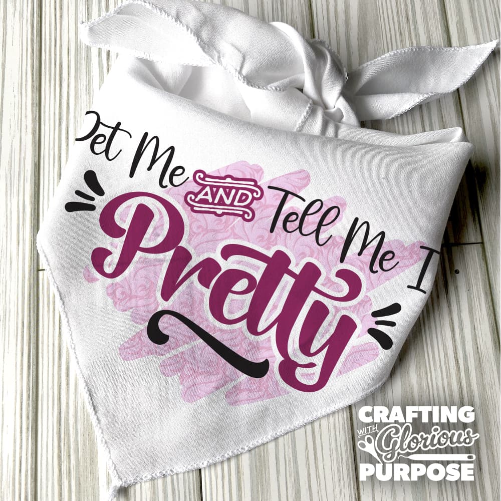 White bandana with decorative text and floral design on a wooden surface, featuring the brand 'Crafting with Glorious Purpose'.