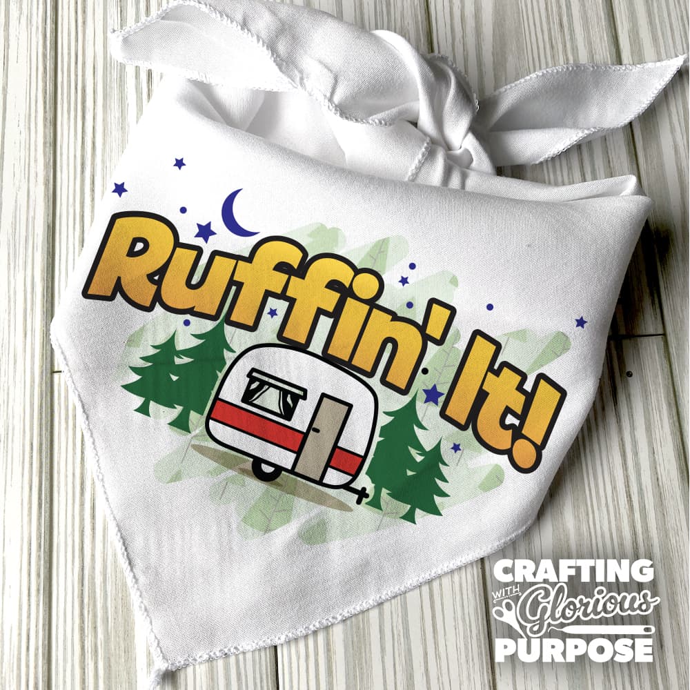 White bandana with 'Ruffin' It!' text and camper graphic on a wooden surface, featuring 'Crafting with Glorious Purpose' branding.