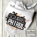 White bandana with 'Squirrel Patrol' text and decorative elements on a wooden surface.