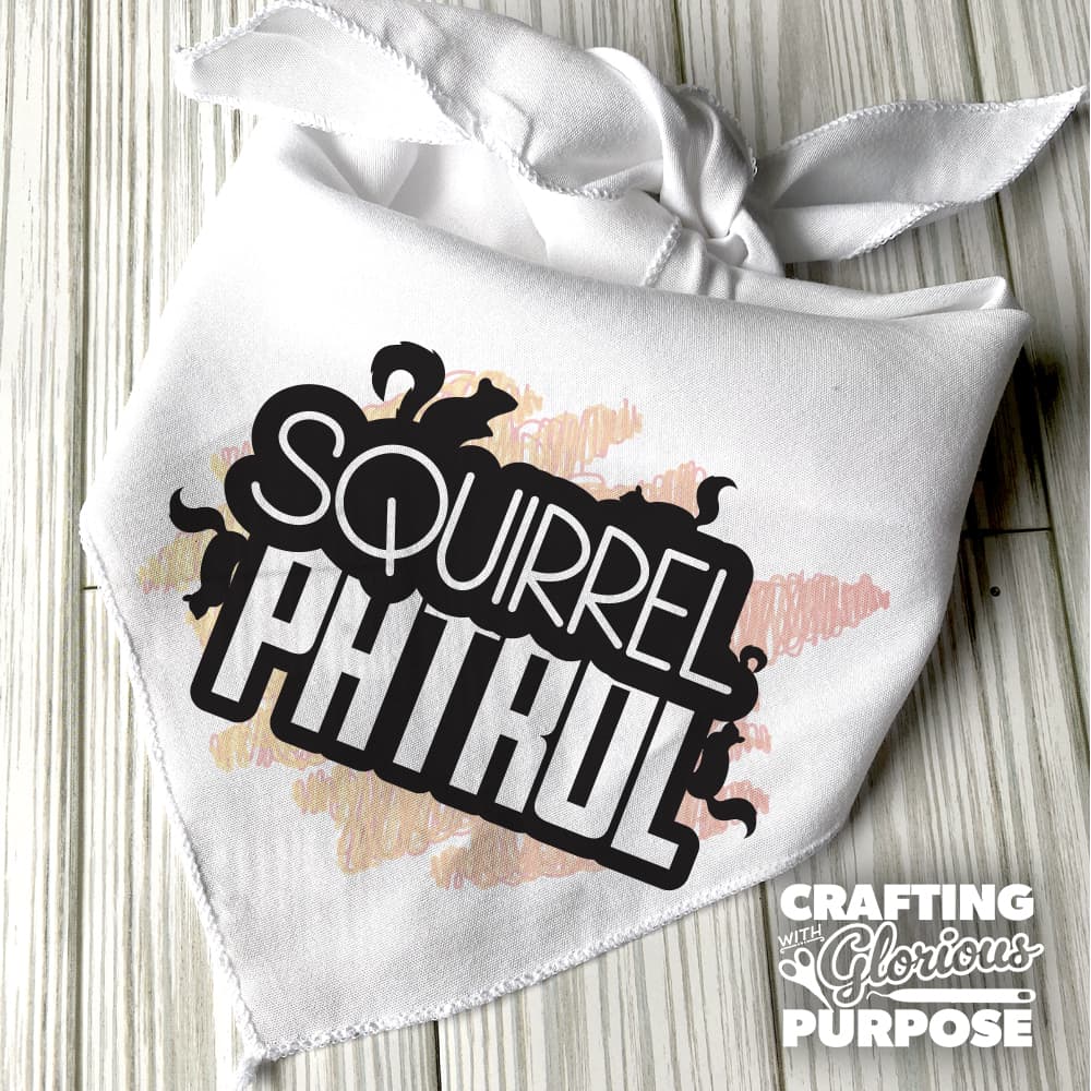 White bandana with 'Squirrel Patrol' text and decorative elements on a wooden surface.