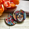 Two circular coasters with floral designs and a dog illustration on a wooden surface with flowers.