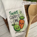 Kitchen towel with cartoon carrot and lime design and wooden spoon on a wooden surface