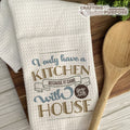 Kitchen towel with humorous quote on a wooden surface with a wooden spoon.