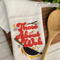 White dish towel with red text and wok illustration on a wooden surface with a wooden spoon.