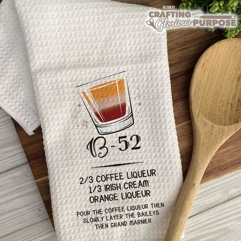 White towel with a drink recipe graphic and wooden spoon on a wooden surface