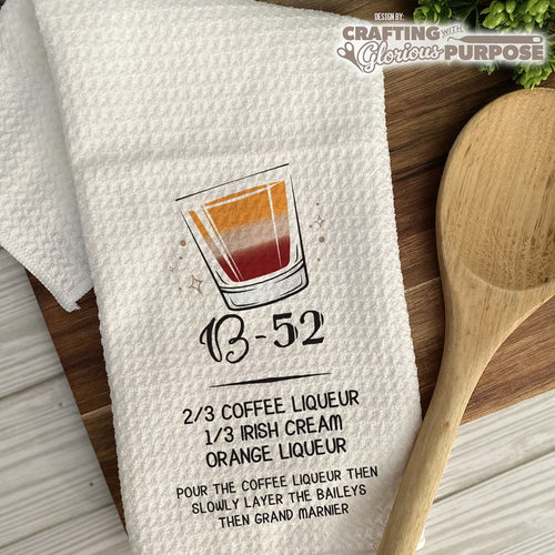 White towel with a drink recipe graphic and wooden spoon on a wooden surface