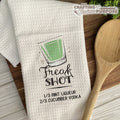White towel with 'Freak Shot' graphic and text, wooden spoon on a wooden surface