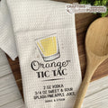 White towel with a drink recipe graphic and wooden spoon on a wooden surface