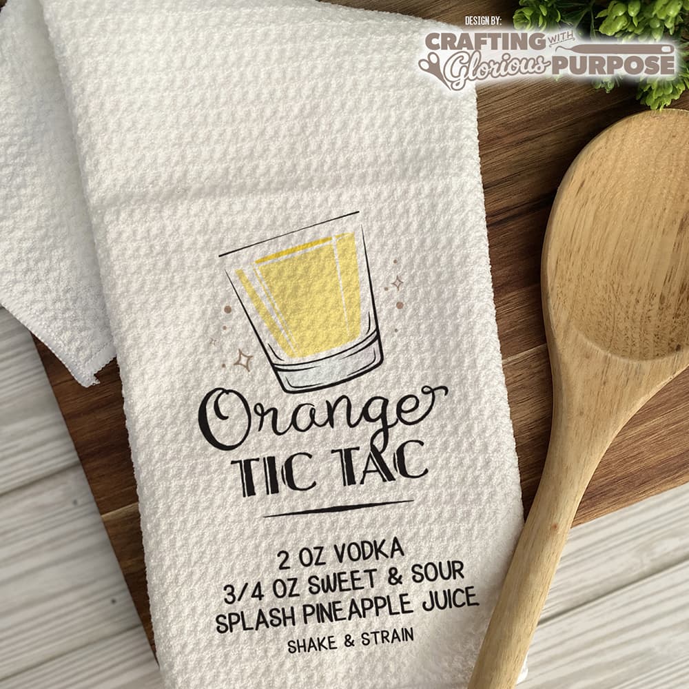 White towel with a drink recipe graphic and wooden spoon on a wooden surface