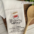 White towel with 'Slippery Nipple' cocktail recipe and wooden spoon on a wooden surface