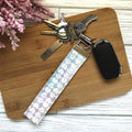 Keychain with floral pattern on a wooden surface with flowers in the background
